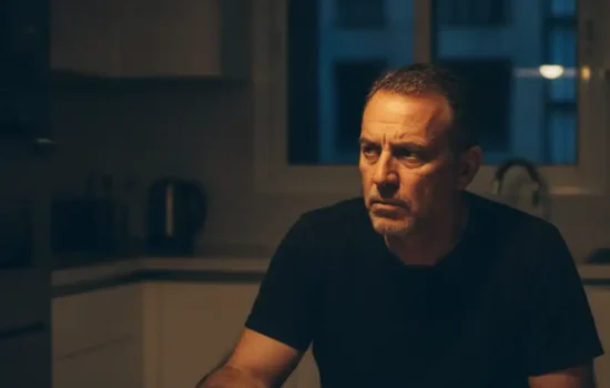 גבר יושב בשולחן המטבח בלילה ליד טלפון הפוך
