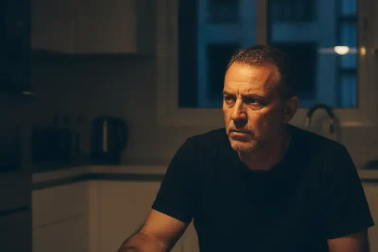 גבר יושב בשולחן המטבח בלילה ליד טלפון הפוך