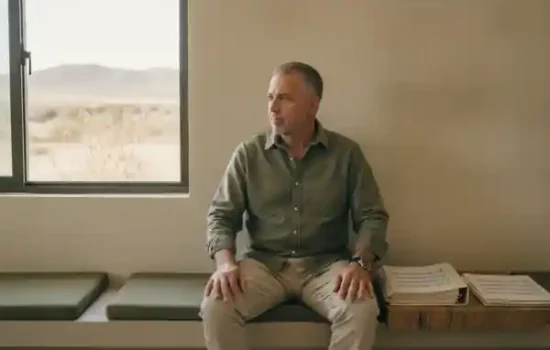 גבר בשנות החמישים ממתין בחדר המתנה שקט עם מסמכים לצדו