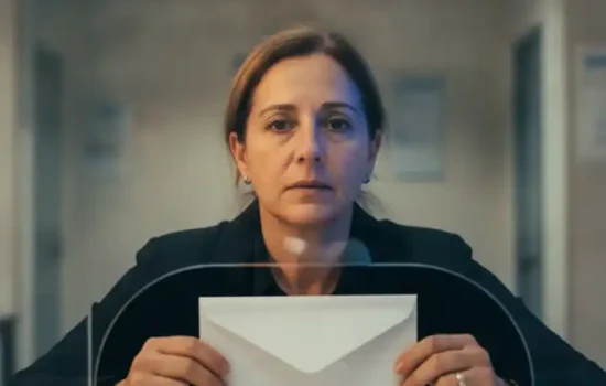 אישה מחזיקה מעטפה ריקה מול דלפק שירות של מוסד ציבורי