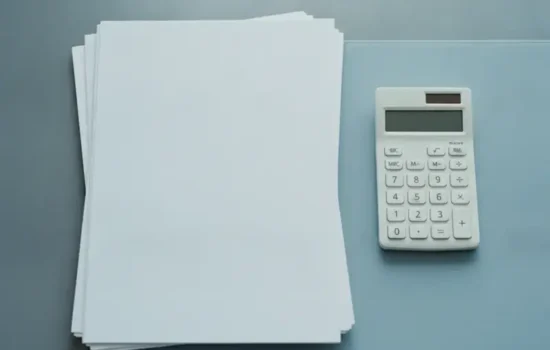 שולחן משרדי עם ערימת דפים ריקים ומחשבון