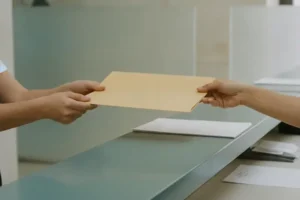 תיקייה סגורה נמסרת בין שתי ידיים מעל דלפק
