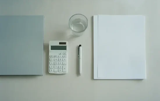 מבט מלמעלה על שולחן עבודה מסודר עם תיקייה, מחשבון ועט לצורך חישוב איזון משאבים