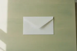 מעטפה לבנה סגורה על שולחן בהיר באור בוקר